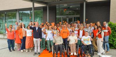 Groep van artsen, verpleegkundigen en personen met MS in het oranje voor de ingang van het MS-Center