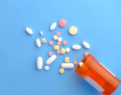 Pillendoosje met allerhande medicatie op een blauwe achtergrond